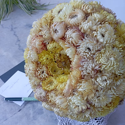 Couronne de deuil en immortelles séchées jaune pâle posée près d'une carte de condoléances, faite main