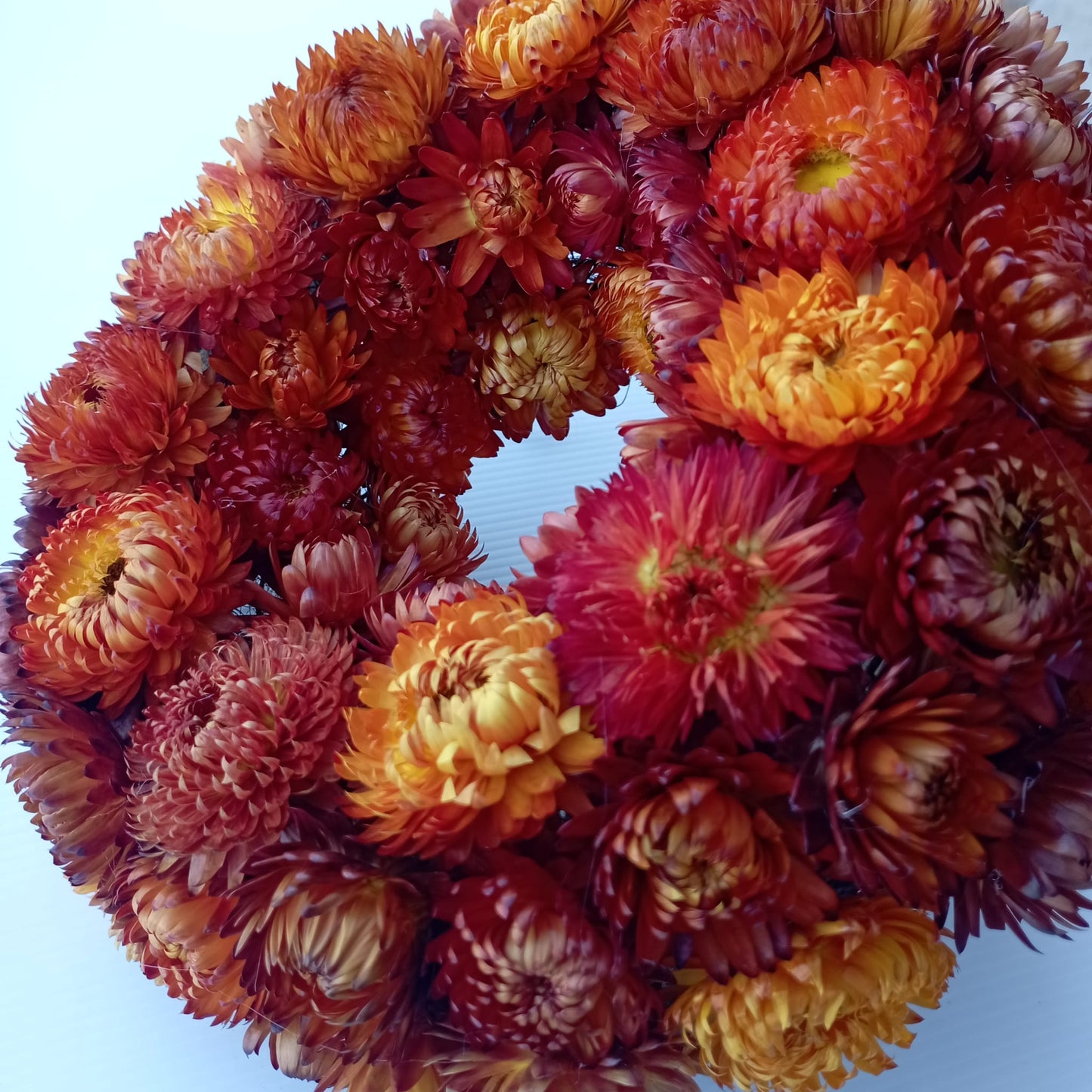 Gros plan sur les immortelles séchées orange et rouge d'une couronne de deuil